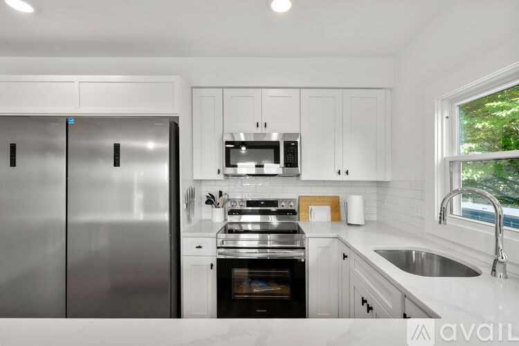 A modern kitchen with a stainless steel refrigerator and white cabinets.