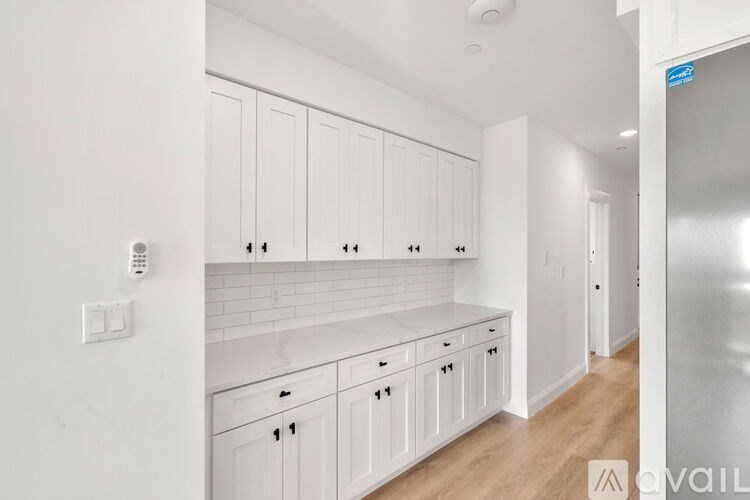 A kitchen with white cabinets and a stainless steel refrigerator.