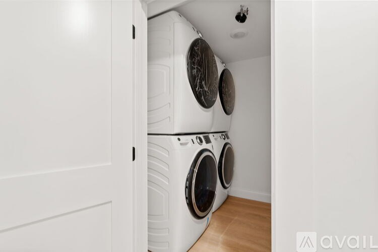 A white door is open to a laundry room with two front-loading washing machines.