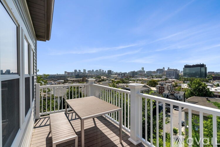 A balcony with a table and chairs overlooking a cityscape.