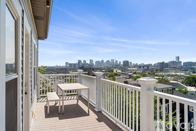A balcony with a table and chairs overlooking a city skyline.