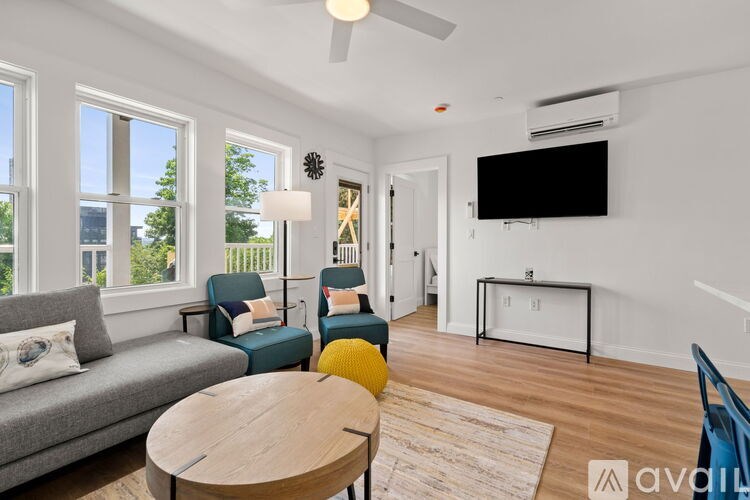 A living room with a grey couch, a wooden coffee table, and a flat screen TV mounted on the wall.