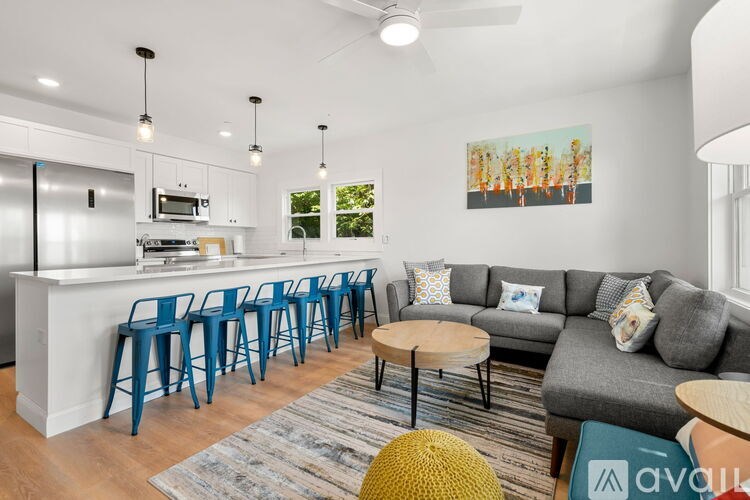 A living room with a grey couch and a bar area with blue chairs.