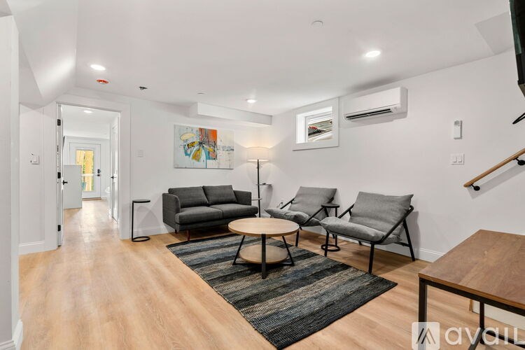 A living room with a grey couch, two chairs and a coffee table.