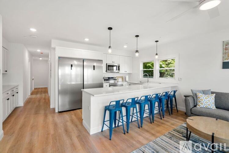 A modern kitchen with blue chairs and a wooden table.