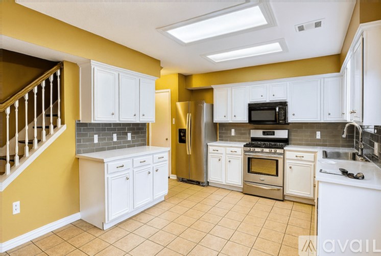 A kitchen with yellow walls and white cabinets.