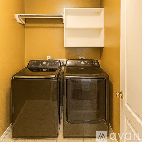 Two black front loading washing machines in a small laundry room.