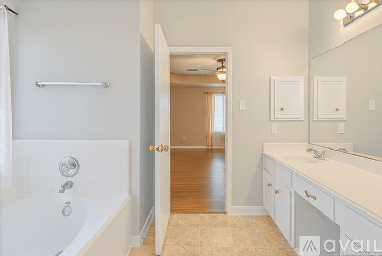 A white bathroom with a tub, sink, and mirror.