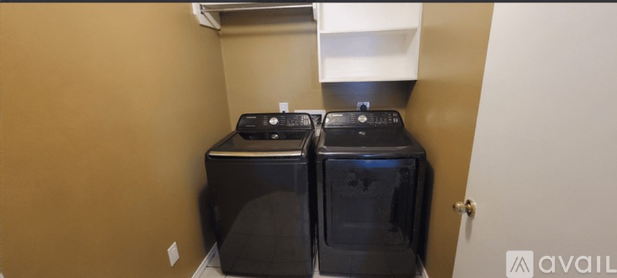 A storage room with a white wall and a black shelf on the left side.