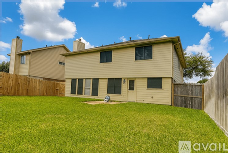 A house with a fence and a lawn in front of it.