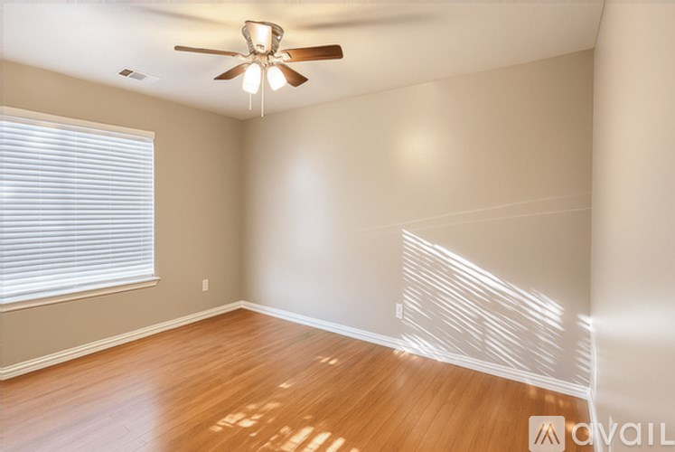 A room with a ceiling fan and wooden flooring.