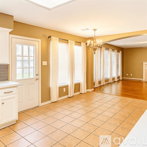 A spacious room with a tiled floor and a chandelier hanging from the ceiling.