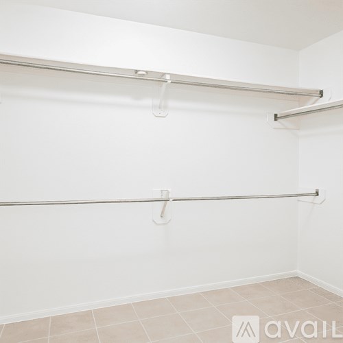 A white wall with a metal rod and two hooks.