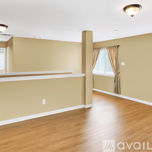 A room with wooden floors and a window with curtains.