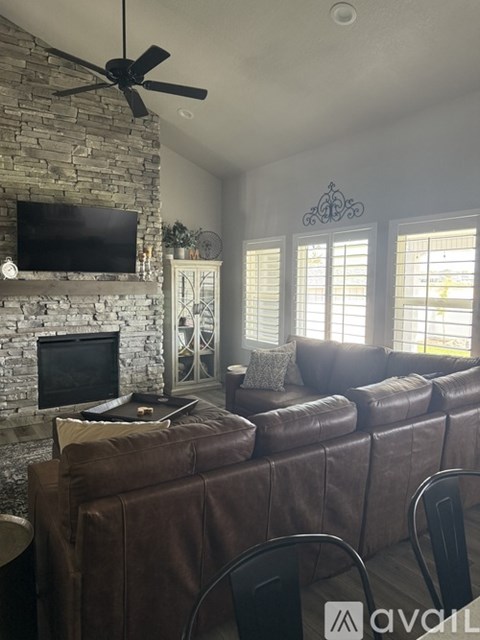 A living room with a brown leather couch and a stone fireplace.