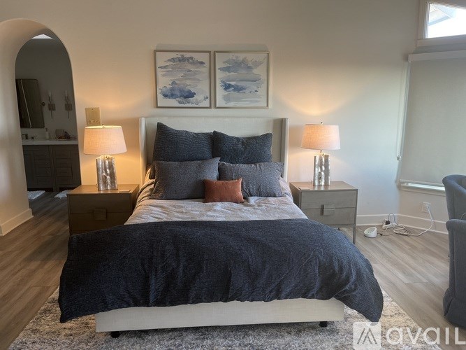 A bedroom with a large bed and two lamps.