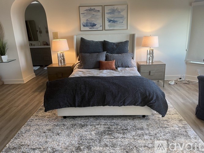 A bedroom with a large bed and two lamps.