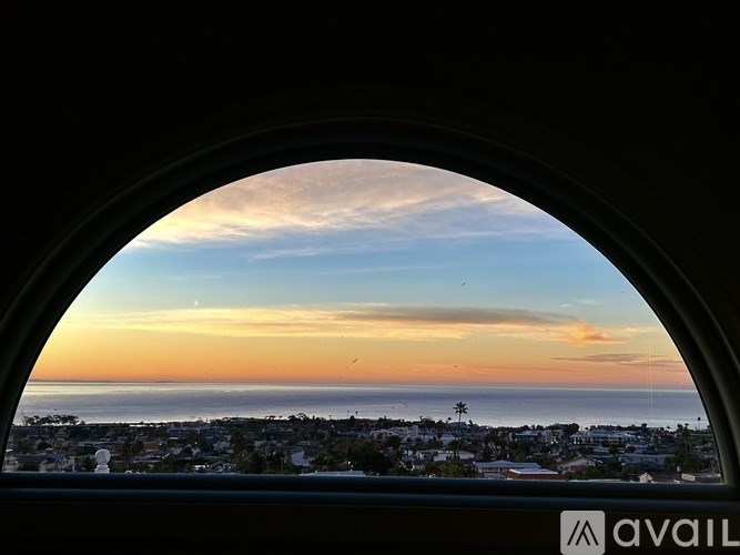 A view of a cityscape through a circular window at sunset.