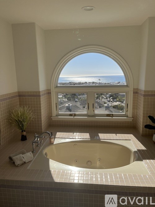 A bathroom with a large tub and a view of the beach through a window.