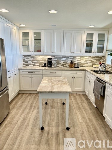 A kitchen with white cabinets and a wooden island.