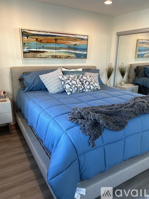 A bed with a blue comforter and pillows in a room.