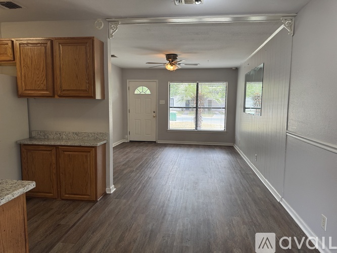 A kitchen area with wooden cabinets and a marble countertop.