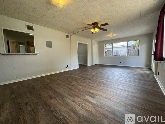 A spacious room with wooden flooring and a ceiling fan.