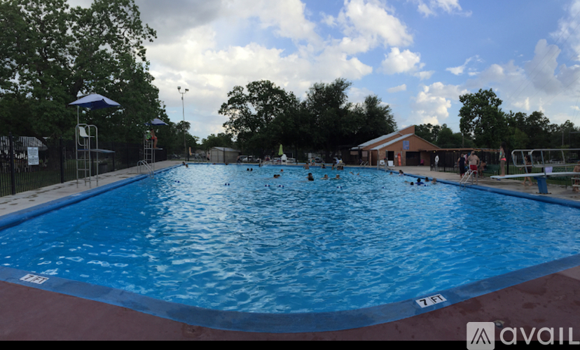 A large outdoor swimming pool with people swimming and sunbathing.