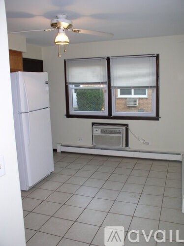 A kitchen with a white fridge and a window with blinds.