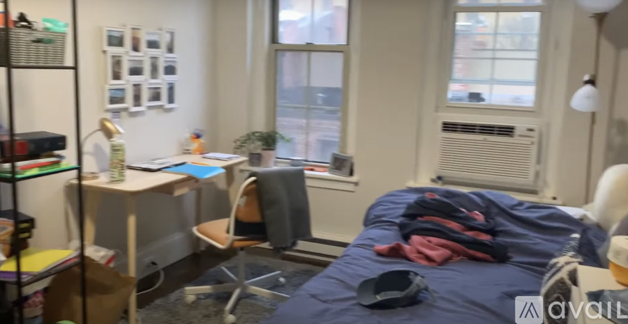 A bedroom with a bed, desk, chair, and window.