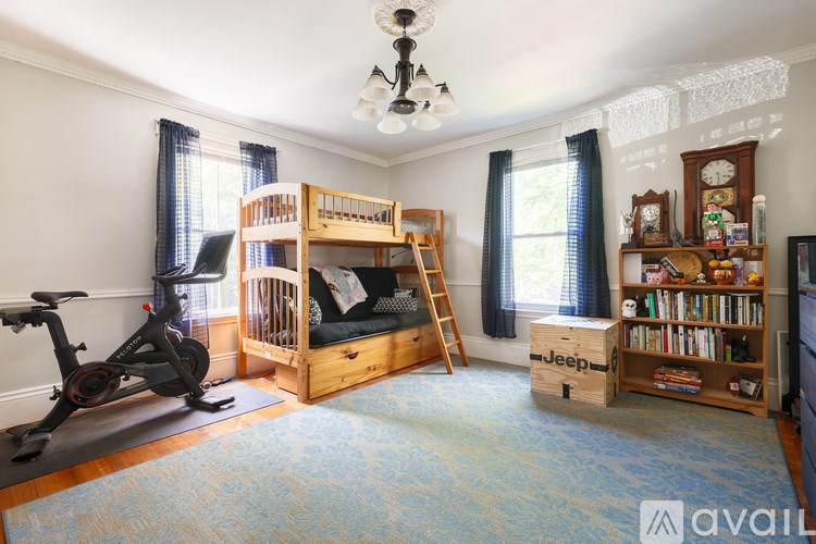 A room with a bunk bed, a bookshelf, and a stationary bike.