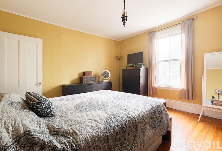 A bedroom with a bed, a dresser, a mirror, and a window.