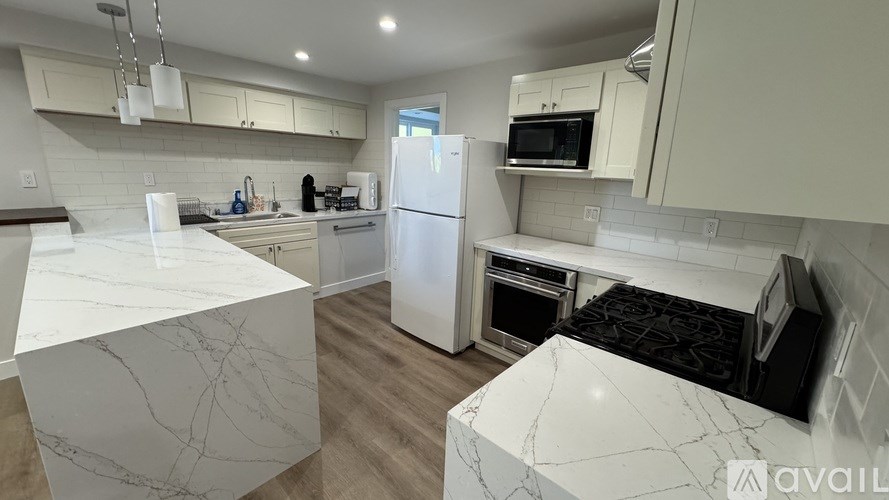 A kitchen with a white fridge and a marble counter top.