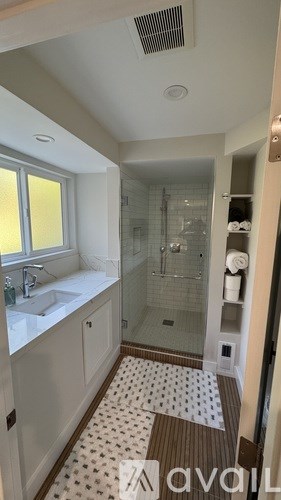 A bathroom with a sink, mirror, and shower.