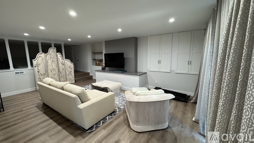 A living room with a sofa, armchair, and television.