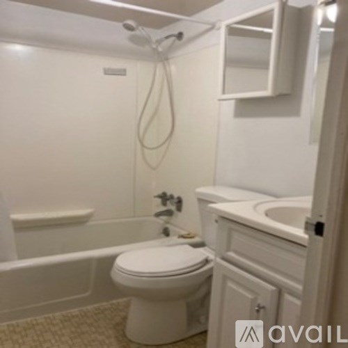 A white toilet sits in a bathroom next to a bathtub.