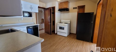 A kitchen with black appliances and wooden floors.