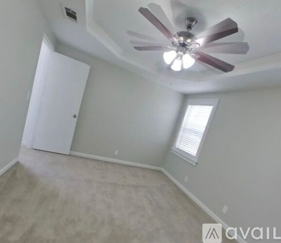 A room with a ceiling fan and a window with blinds.