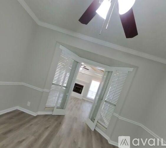 A room with a ceiling fan and a doorway leading to another room.