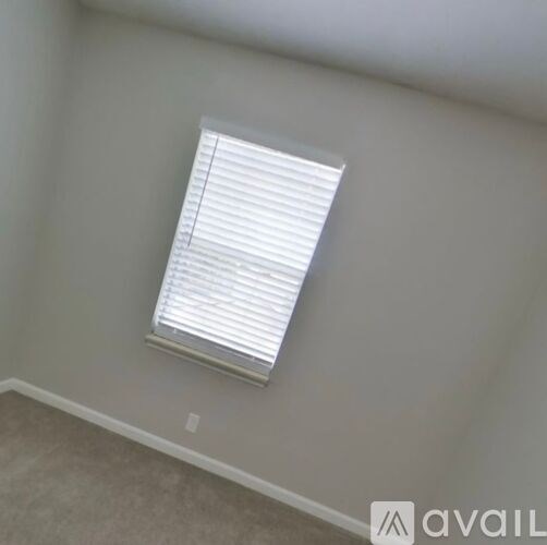 A window with white blinds in a room.