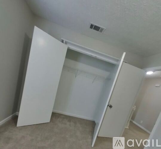 A white closet with a door open is in a room with white walls.