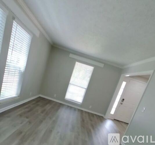 A room with a window and a door is available for rent.