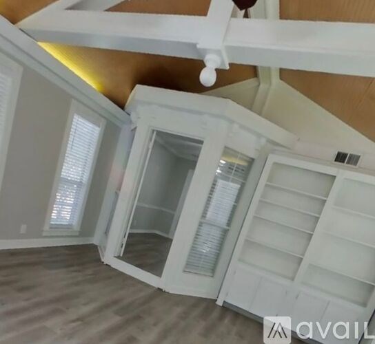 A kitchen with white cabinets and a wooden ceiling.