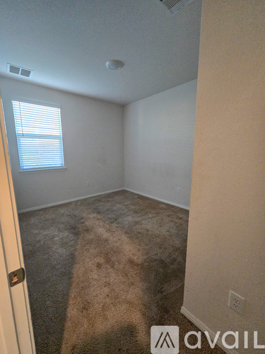 A room with a carpeted floor and a window with blinds.
