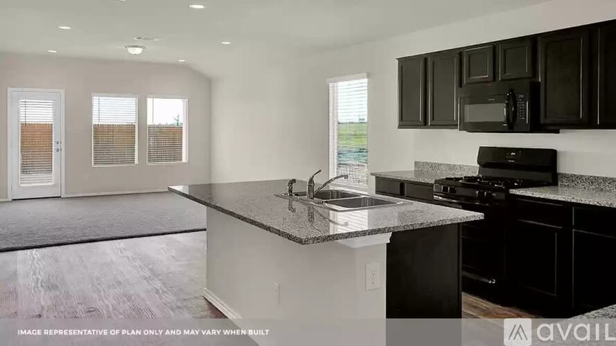 A kitchen with black cabinets and a granite countertop.