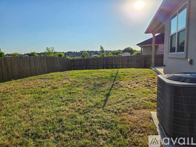 A backyard with a fence and a house with a window.