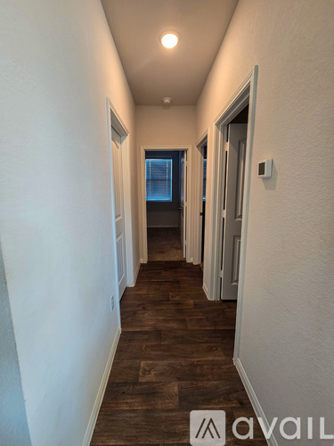 A long hallway with wood floors and white walls.