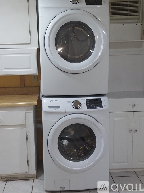 A white washing machine and dryer stacked on top of each other in a kitchen.