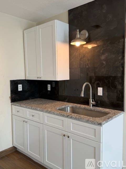 A kitchen with white cabinets and a granite countertop.