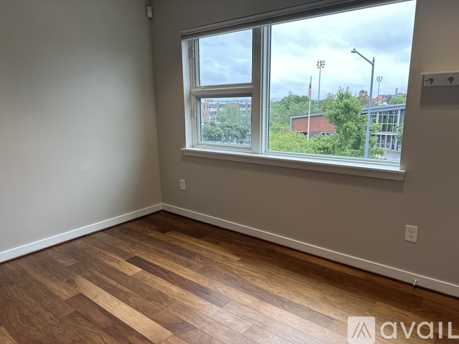 A room with wooden flooring and a door on the right.